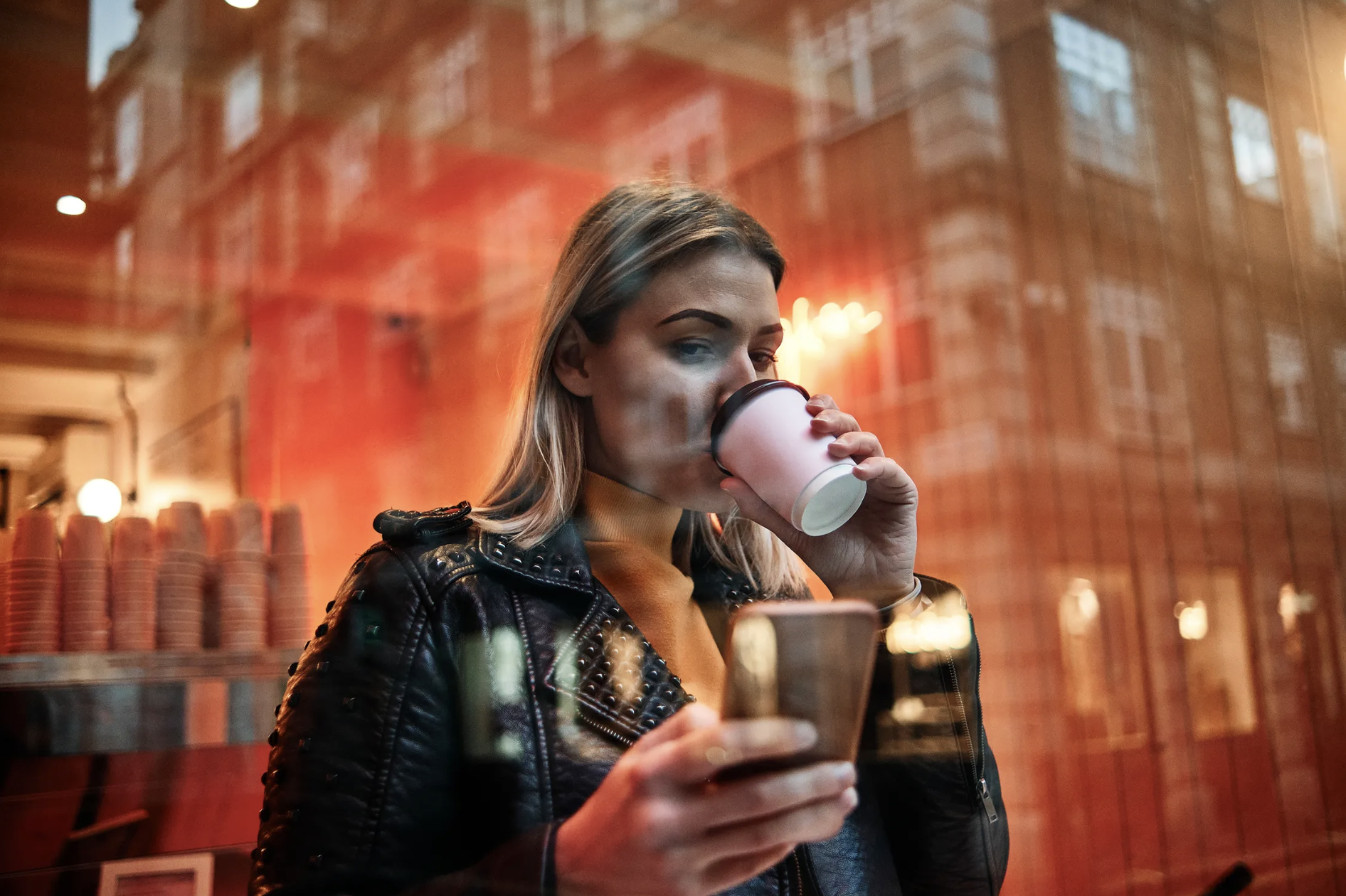 Woman holding a phone drinking a coffee